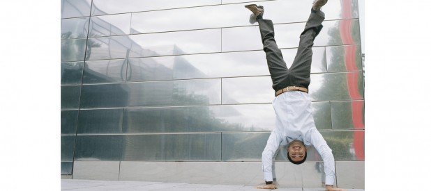 Business man doing handstand outside in front of office building