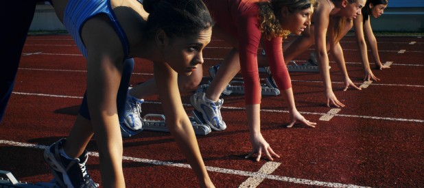 Four Female Athletes (18-21) in Starting Blocks Awaiting the Race Start