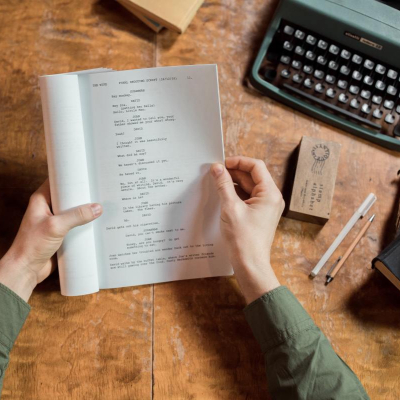 Image of hands holding a screenplay open to a page of text
